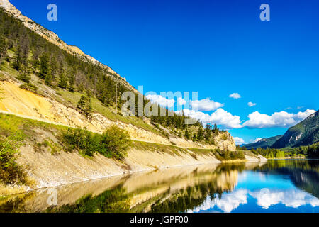 Blauer Himmel, Bäume und Berge reflektieren die glatte Oberfläche auf dem kristallklaren Wasser des Krone-Sees entlang Highway 99 in Marble Canyon, BC, Kanada Stockfoto