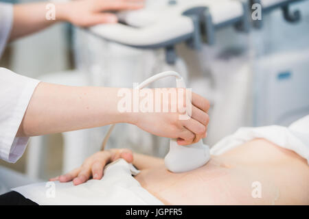 Nahaufnahme des Arztes bewegen Ultraschallsonde auf Bauch der schwangeren Frau im Krankenhaus Stockfoto