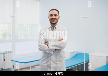 Porträt von einen glücklichen männlichen Arzt Stand mit verschränkten im medizinischen Büro Stockfoto