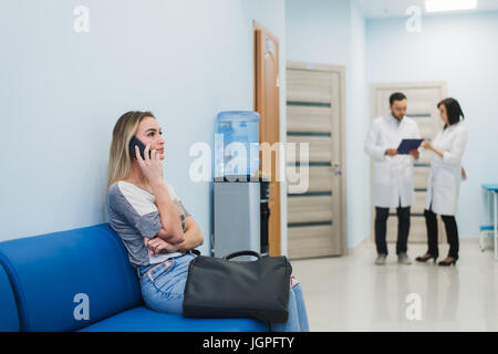 Frau Patienten sprechen auf das Handy im Krankenhaus Wartezimmer. Stockfoto