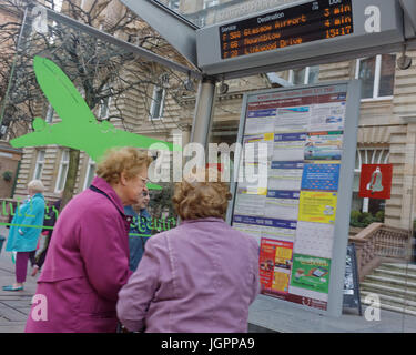 alte Damen Beratung Busfahrplan an einer Bushaltestelle mit Jet Flugzeug Aufkleber und Flughafen Businformationen über Scanner an Bord St Vincent Street Glasgow Schottland Stockfoto