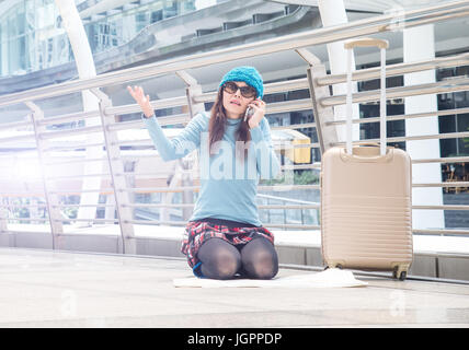 Touristen Mädchen asiatische Suche Lage in einem Reiseführer Karte und Smartphone mit Flughafen im Hintergrund Stockfoto