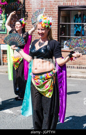 Tribal Banshees Bauchtanz Damen, 30s 40s, Tanzen im Freien im sonnigen Straße. Winkenden Fans und mit Girlande mit Blumen im Haar. Um im Alter von Mitte dreißig bis Anfang der vierziger Jahre. Folk Festival Veranstaltung. Stockfoto