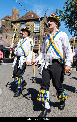 Traditionelle englische Volkstänzer, Yateley Morris Seite tanzen auf der Straße in der mittelalterlichen Stadt Sandwich während des Folk und Ale-Festival. Holding Polen. Stockfoto