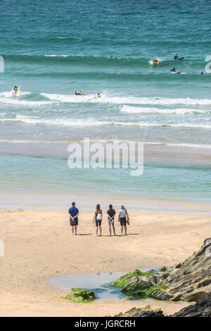 Urlauber am Fistral Strand beobachten Surfer im Meer. Stockfoto