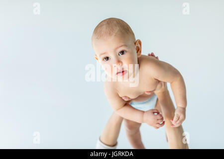 Vorderansicht des entzückenden jungen über den Kopf halten Mutter isoliert auf grau, 1 Jahr alt Baby Konzept Stockfoto