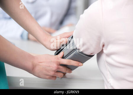 Schuss von Krankenschwester Patienten Blutdruckmanschette gesetzt beschnitten Stockfoto