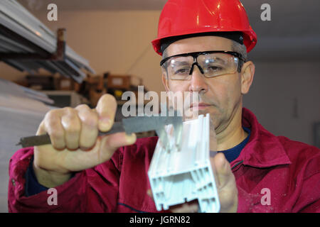 Mechanische Techniker messen mit Bremssattel in Werkstatt für die Herstellung von PVC-Fenstern. Stockfoto