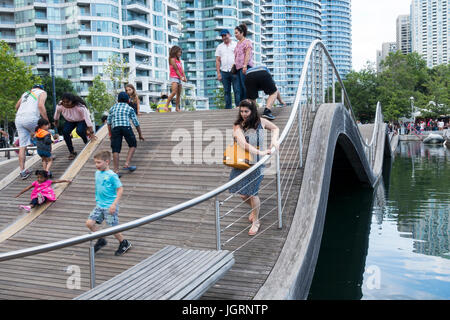 Touristen und Fußgänger versuchen, auf dem Simcoe Wave Deck zu laufen, einem fantasievollen Beispiel urbaner Kunst am Harbourfront in der Innenstadt von Toronto, Ontario. Stockfoto