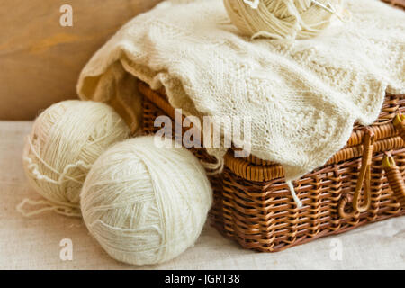 Alte Vintage Wicker Hobby Truhe auf Leinenstoff mit weißer Wolle Clews, Handarbeiten auf rustikalen Holz Hintergrund, stricken, Basteln, Konzept, Banner, Header ich Stockfoto