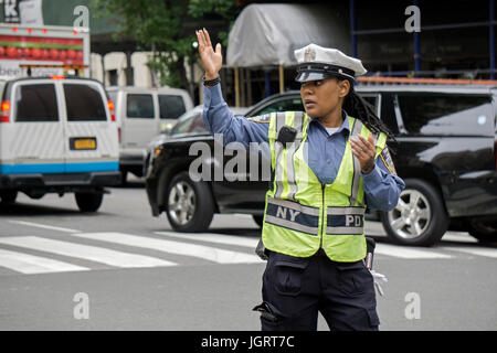 Eine attraktive Polizistin mit langen Fingernägeln, die Regelung des Verkehrs auf der 34th Street in Manhattan, New York City Stockfoto