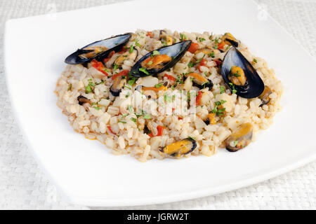 Schüssel mit gemischten Getreide, Reis, Dinkel und Gerste, mit Muscheln zubereitet. Gewürzt mit Tomatensauce und Topinambur. Stockfoto