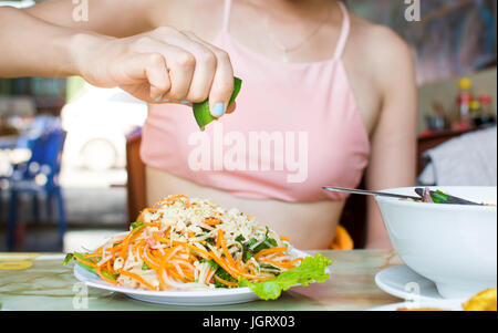 Weibliche Hand drückte Kalk auf Thai grüne Papaya-Salat Stockfoto