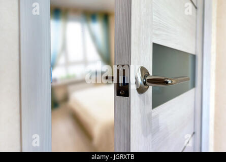 Close-up-Elemente des Innenraums der Wohnung. Einen Spaltbreit weiße Tür. Chrom Türgriff. Stockfoto