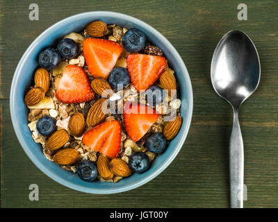 Frühstück Müsli Müsli mit Erdbeeren und Blaubeeren Obst vor einem grünen Hintergrund Stockfoto