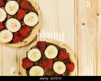 Pfannkuchen mit Schokolade mit Banane und Himbeeren gegen eine Kiefer Holz Hintergrund Stockfoto