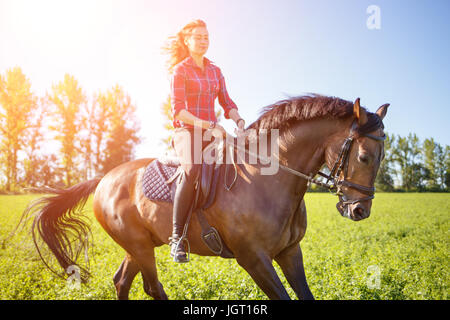 Glückliche Mädchen reiten auf der grünen Wiese am sonnigen Tag zu genießen Stockfoto