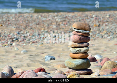 Pyramide aus farbigen Kieselsteinen an einem sonnigen Strand Stockfoto