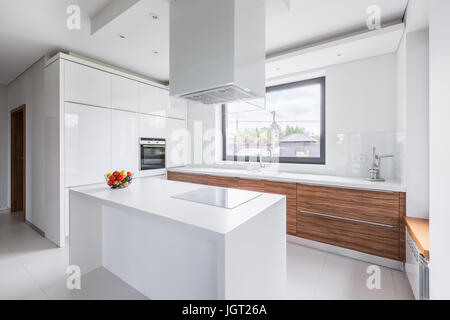 Weiße Küche mit Insel, lange Arbeitsplatte und hölzerne Schränke