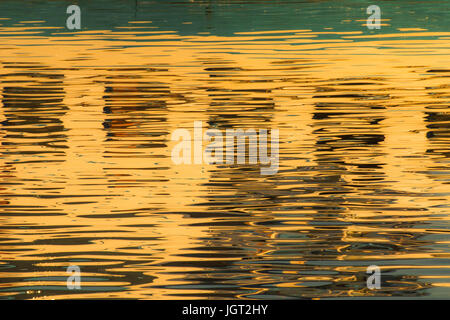 Reflexion von Fenstern in den Wassern des Sees erstellt durch das Licht der untergehenden Sonne bilden unterschiedlicher Größe und Form der Schimmer und Farben Stockfoto
