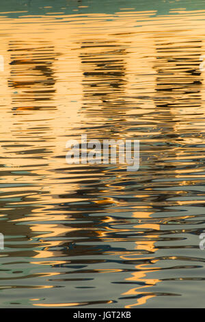 Reflexion von Fenstern in den Wassern des Sees erstellt durch das Licht der untergehenden Sonne bilden unterschiedlicher Größe und Form der Schimmer und Farben Stockfoto