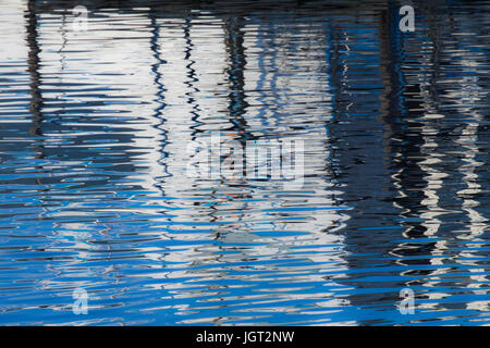 Reflexion eines Piers in den Wassern des Sees erstellt durch das Licht der untergehenden Sonne bilden unterschiedlicher Größe und Form der Schimmer und Farben Stockfoto