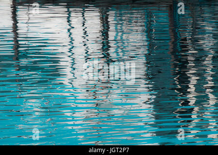 Reflexion eines Piers in den Wassern des Sees erstellt durch das Licht der untergehenden Sonne bilden unterschiedlicher Größe und Form der Schimmer und Farben Stockfoto