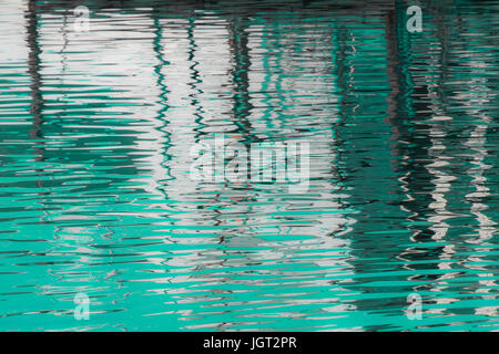 Reflexion eines Piers in den Wassern des Sees erstellt durch das Licht der untergehenden Sonne bilden unterschiedlicher Größe und Form der Schimmer und Farben Stockfoto