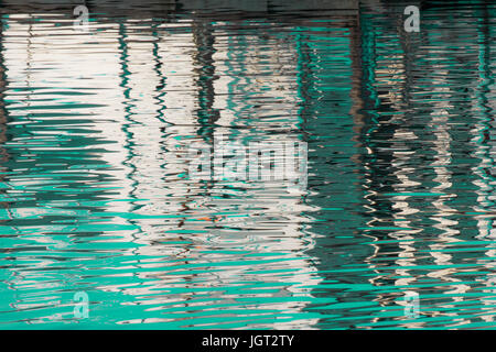 Reflexion eines Piers in den Wassern des Sees erstellt durch das Licht der untergehenden Sonne bilden unterschiedlicher Größe und Form der Schimmer und Farben Stockfoto