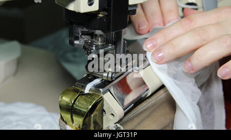 Porträt von Händen der Schneiderin Nähen mit Industrienähmaschine hautnah. Stockfoto