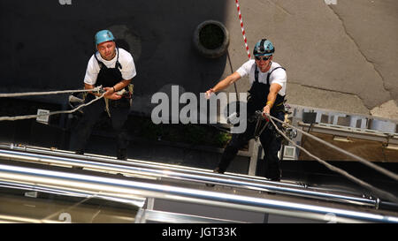 Arbeiter an Kletterseilen, hängen Daumen Schild zeigt. Stockfoto