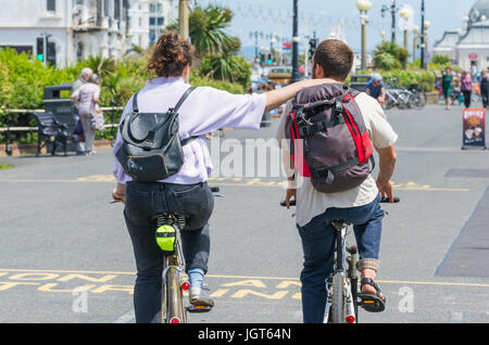 Ein paar Radfahren gemeinsam berühren Arme entlang der Strandpromenade. Stockfoto