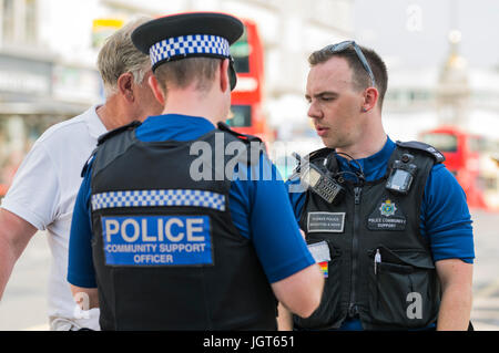 PCSOs (Police Community Support Officers) im Gespräch mit jemand auf den Straßen von Brighton, East Sussex, England, UK. Stockfoto