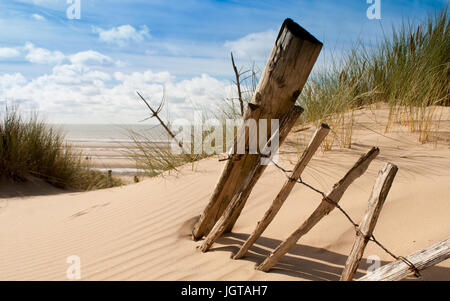 Seascape Ansicht eines gebrochenen alten Zaun Reste auf einer Düne mit Blick auf das Meer im Hintergrund Stockfoto