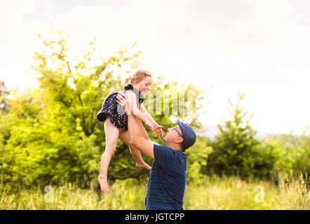 Junger Vater in der Natur, die kleine Tochter in den Armen hielt. Stockfoto