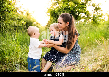 Junge Mutter mit kleinen Kindern im sonnigen Sommer-Natur Stockfoto