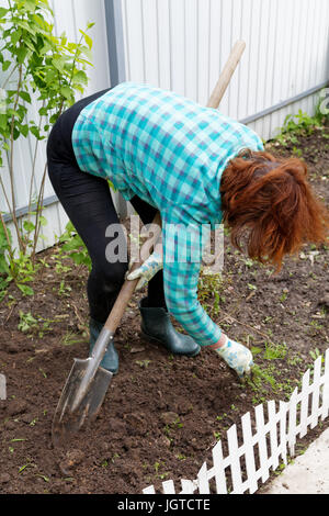 Graben den Boden mit einer Schaufel mit einer Großaufnahme eines Gartens Frau Stockfoto