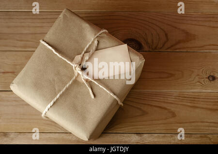 Overhead Schuss eines Flurstücks braune Papiertüte mit Schnur gebunden.  Leeres Etikett nach oben zu textfreiraum bieten Flächen.  Legen Sie auf einem alten, abgenutzten Holztisch. Stockfoto