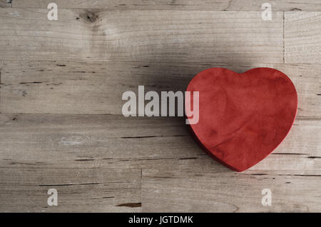 Overhead Schuss ein rotes Herz geformt Holzkiste, mit Suedette Textur auf einem alten Holztisch geplankte gemalt.  Liebe oder Valentinstag-Konzept. Stockfoto