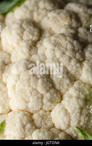 Nahaufnahme (Makro) von frischen, rohen Blumenkohl mit Röschen intakt und grüne Blätter sichtbar. Stockfoto