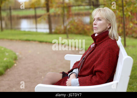 Nachdenklich senior Frau sitzt auf einer Bank im Park Stockfoto