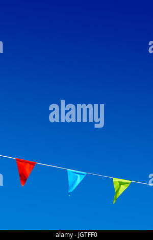 Drei bunte Party-Fahnen im Wind gegen blauen Himmel. Stockfoto