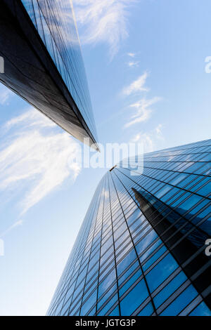 Niedrigen Winkel auf Wolkenkratzer und Glasbauten mit blauem Himmel in einer geometrischen Anordnung. Stockfoto
