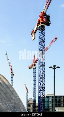 Vier Turmdrehkrane auf einer Baustelle mitten in einem Geschäftsviertel in voller Entwicklung. Stockfoto