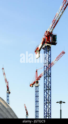 Vier Turmdrehkrane auf einer Baustelle mitten in einem Geschäftsviertel in voller Entwicklung. Stockfoto