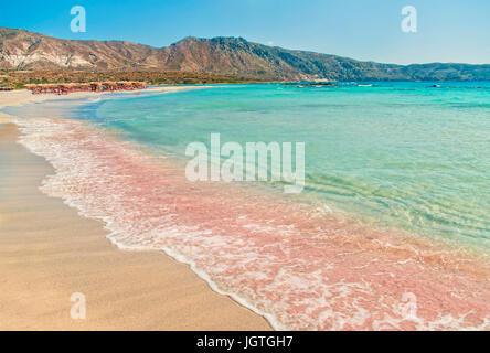 einzigartige Elafonisi-Strand mit rosa Sand und Wellen des Mittelmeeres mit Bergen im Hintergrund an sonnigen Sommertag, Kreta, Griechenland Stockfoto