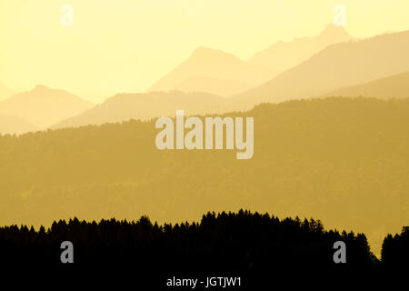 Spektakuläre Aussicht auf die Berge Silhouetten. Gelbe Sonnenlicht in den frühen Morgen. Stockfoto