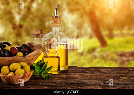 Frisch geerntete Oliven Beeren in Holz Schalen und kaltgepresstes Öl in Glasflaschen. Stillleben der Zubereitung von Speisen serviert auf alten Holzdielen. Kostenlose spac Stockfoto
