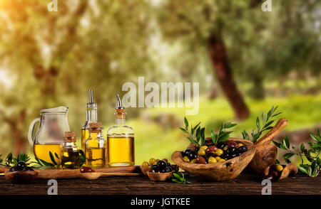 Frisch geerntete Oliven Beeren in Holz Schalen und kaltgepresstes Öl in Glasflaschen. Stillleben der Zubereitung von Speisen serviert auf alten Holzdielen. Kostenlose spac Stockfoto