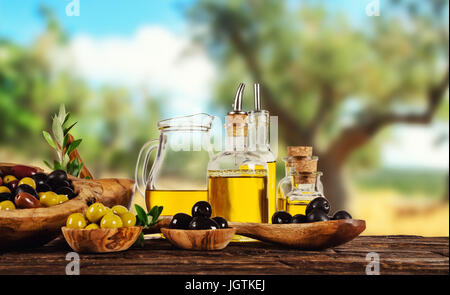 Frisch geerntete Oliven Beeren in Holz Schalen und kaltgepresstes Öl in Glasflaschen. Stillleben der Zubereitung von Speisen serviert auf alten Holzdielen. Kostenlose spac Stockfoto